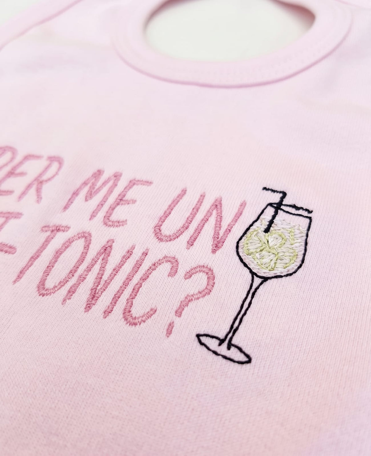Dettaglio del ricamo Per me un Lat-Tonic e del calice sulla bavetta rosa
