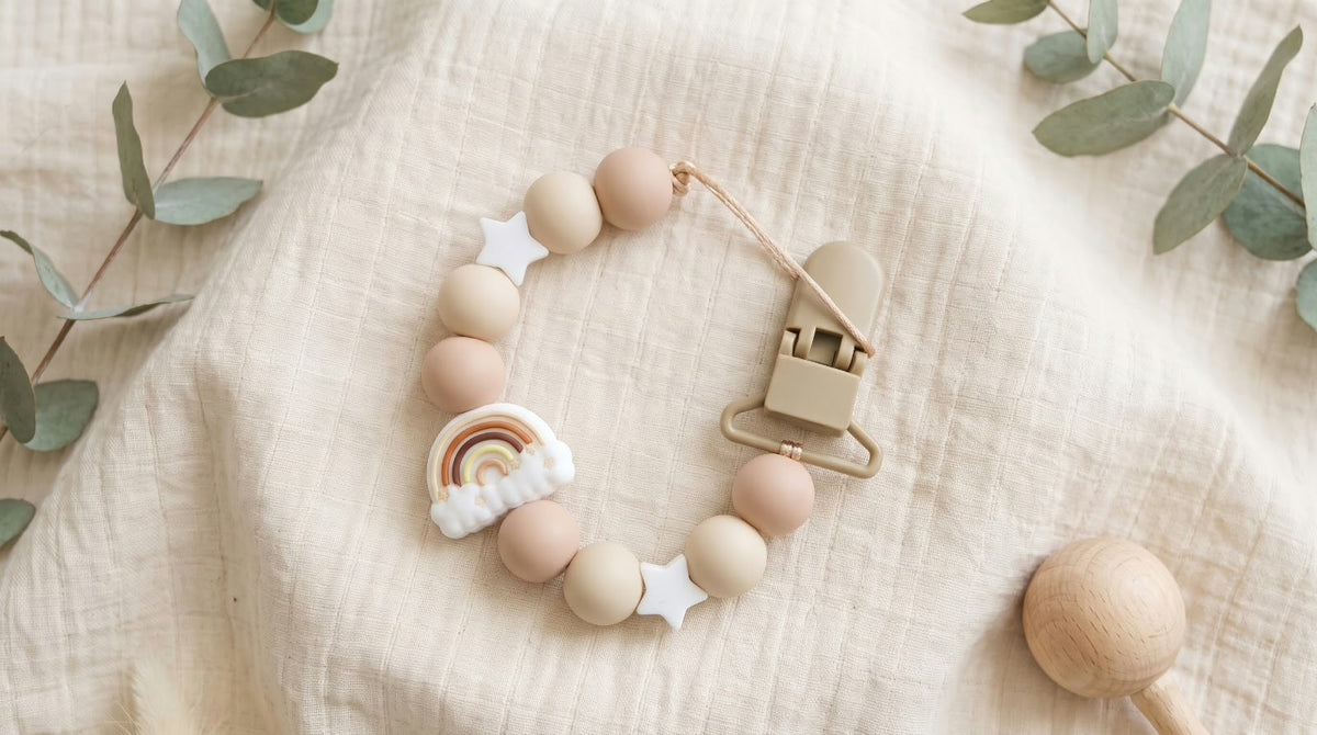 Dettaglio del charm arcobaleno e delle perline in silicone beige
