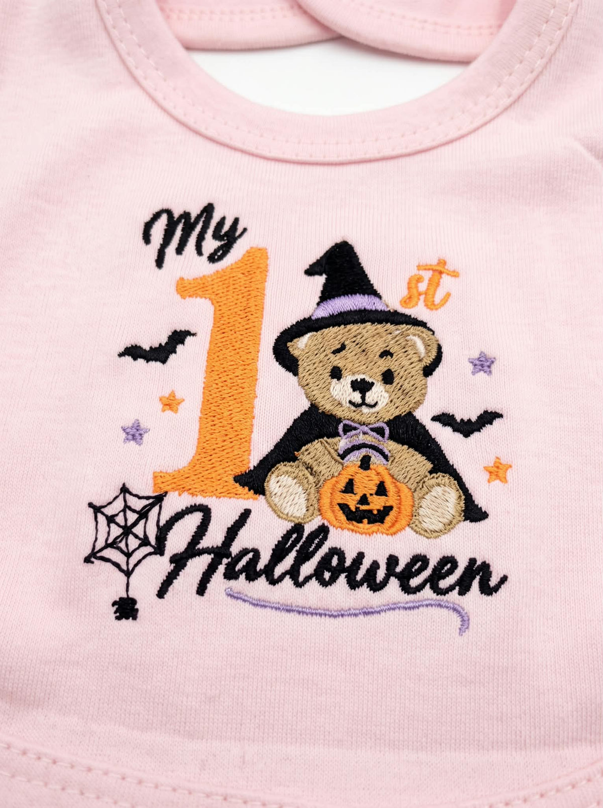 Dettaglio ricamo My 1st Halloween con orsetto streghetta sulla bavetta rosa